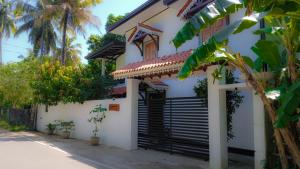 a white house with a gate and palm trees at The White Crane Koggala in Habaraduwa Central