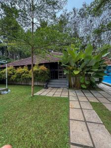 a house with a tree in front of a yard at Maple grove villa resort in Panamaram