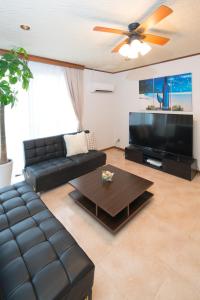 a living room with a black leather couch and a flat screen tv at 禅 Zen 鹿児島 フロア貸切 中央駅徒歩14分 in Yamashitachō