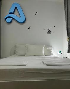 a white bed with a blue letter on the wall at Adam's Apartment 2 in Kladovo