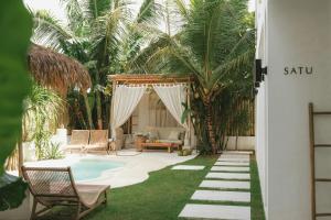 a backyard with a pool and chairs and palm trees at Tyde Bali Boutique Hotel in Uluwatu +44 photos