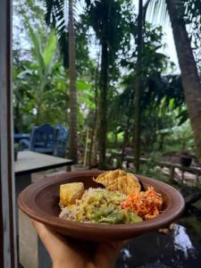 a person holding a plate of food in their hand at Viveka Inn Guest and Yala Safari in Tissamaharama
