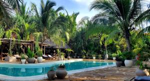 a pool at a resort with palm trees at Promised Land Lodge in Kizimkazi