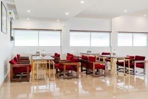 a dining room with tables and red chairs and windows at Treebo Skyline in Mangalore