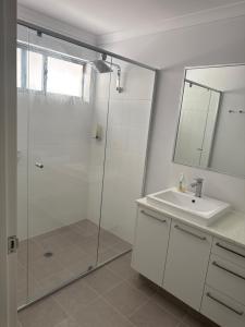 a bathroom with a glass shower and a sink at Beach House Shared in Alkimos +10 photos