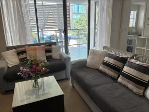 a living room with a couch and a vase of flowers on a table at Merivale stay in South Brisbane two beds two baths one parking in Brisbane