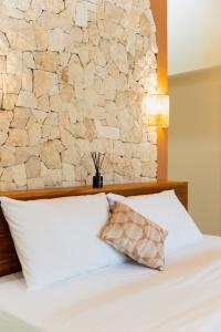 a bedroom with a white bed with a stone wall at Los Londos Batukaras in Cijulang Nusawiru Airport