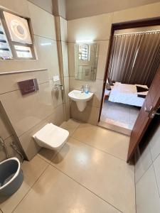 a bathroom with a toilet and a sink and a bed at Valensa lake view in Kalpetta