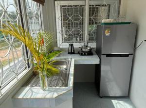 a kitchen with a refrigerator and a sink and a window at Penn house with shared pool in Ko Raeng