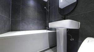 a bathroom with a sink and a tub and a mirror at 호텔 페르소나 in P'ungnyŏn-gol