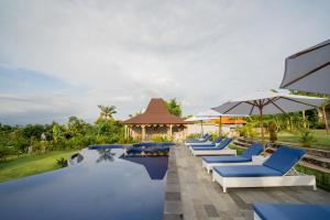 a pool with blue chairs and umbrellas at a resort at Ratna's Green Hill Penida by Bali Cabin in Nusa Penida