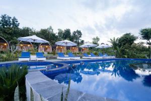 a swimming pool with blue chairs and umbrellas at Ratna's Green Hill Penida by Bali Cabin in Nusa Penida