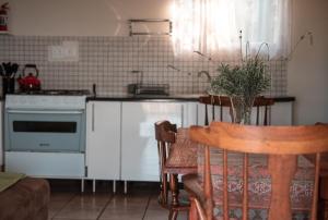 a kitchen with a stove and a table with a chair at Chilli cottage - off grid get away in Mkondeni +3 photos