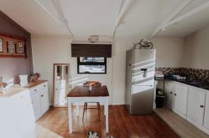 a kitchen with a table and a refrigerator at Chilli cottage - off grid get away in Mkondeni