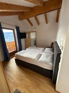 a large bed in a room with a large window at Hohenbichl in Terento