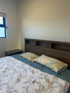 a bedroom with a bed with a wooden headboard and two pillows at Deva house in Box Hill