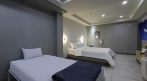 a hotel room with two beds and a tv at 호텔 페르소나 in P'ungnyŏn-gol