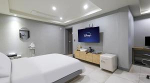 a bedroom with a white bed and a tv on the wall at 호텔 페르소나 in P'ungnyŏn-gol