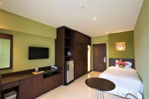 a bedroom with a bed and a flat screen tv at Chateau de Sukhumvit in Bangkok