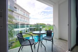 a balcony with a table and chairs and a pool at Cozy Resort, A Boutique Hotel in Pattaya South