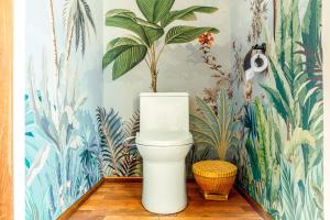a white toilet in a bathroom with tropical wallpaper at Kama Haven in Semaya +43 photos