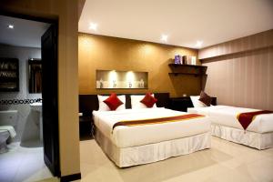 a hotel room with two beds and a bathroom at Chateau de Sukhumvit in Bangkok