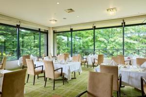 a restaurant with white tables and chairs and windows at Hotel Marroad Karuizawa in Karuizawa