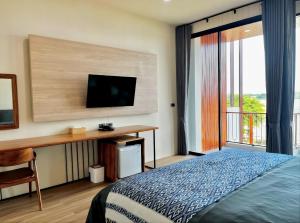 a bedroom with a bed and a desk with a television at บ้านเคียงสะหวัน in Muang Phaluka
