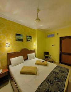 a bedroom with a large bed with yellow walls at amb guest house in Chennai