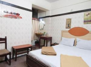 a bedroom with a bed and two chairs and a table at amb guest house in Chennai