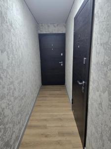 a hallway with a black door and a wooden floor at В Центре Экибастуза in Ekibastuz