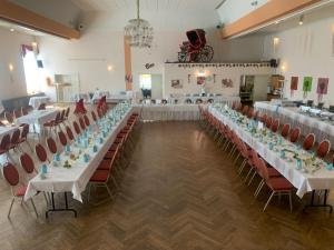 a large banquet hall with white tables and red chairs at Hotel Schwarzes Ross Siebenlehn in Siebenlehn