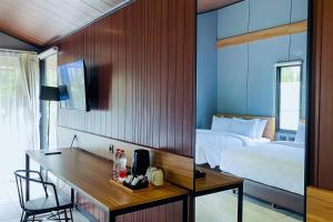 a bedroom with a bed and a desk and a bed and a room with at Alfa Jivana Resort in Sampal 2