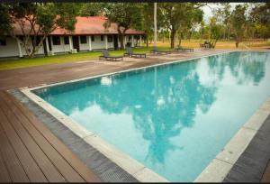 ein großer blauer Swimmingpool mit Bänken in einem Garten in der Unterkunft Yatra Negambo in Katunayaka