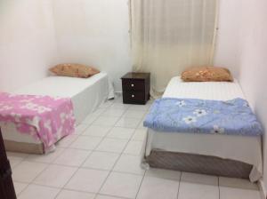 a room with two beds and a night stand at IMADUDDEEN Homestay in Kampong Bukit Kuang