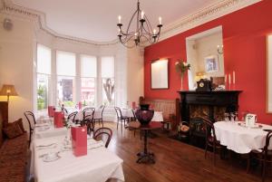 a restaurant with red walls and tables and a fireplace at Southside Guest House in Edinburgh