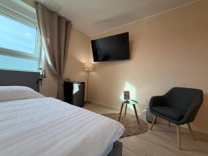 a bedroom with a bed and a chair and a television at City Inn Schwedt in Schwedt
