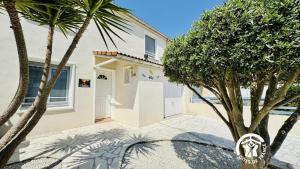 a white house with palm trees in front of it at La douce echappée in Trèbes