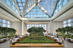 a large lobby with tables and chairs and palm trees at Park Hyatt Tokyo in Tokyo
