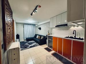 a kitchen and a living room with a couch in it at Malamaya Staycation in Manila