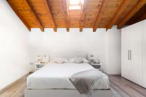 a bedroom with a white bed with a wooden ceiling at Luxury Lakeview Loft in Baveno