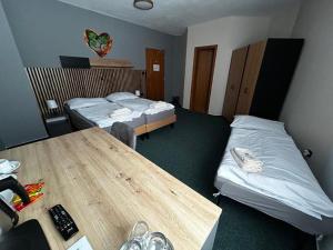 a hotel room with two beds and a wooden table at HOTEL Tyrapol - izby in Oravská Lesná