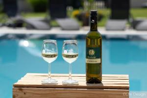 a bottle of wine and two wine glasses next to a pool at Rebenhof Schwalm in Herrnbaumgarten +17 photos