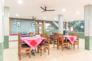 a dining room with tables and chairs with pink tablecloths at Treebo Pratham Inn Water Park Resort With Swimming Pool in Kundapur