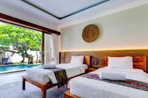 two beds in a room with a window at The Daun Bali in Canggu +43 photos