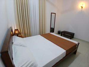 a bedroom with a large white bed with a mirror at Noel Villa in Galle