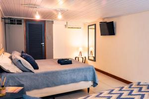 a bedroom with a bed and a tv on the wall at Suites Belos Ares in Búzios