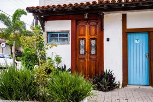 a house with a wooden door and blue doors at Suites Belos Ares in Búzios