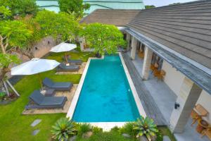 an overhead view of a swimming pool with chairs and umbrellas at The Daun Bali in Canggu