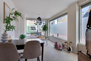 a dining room with a table and chairs and windows at DuoSuite Sand Vrouwenpolder in Vrouwenpolder